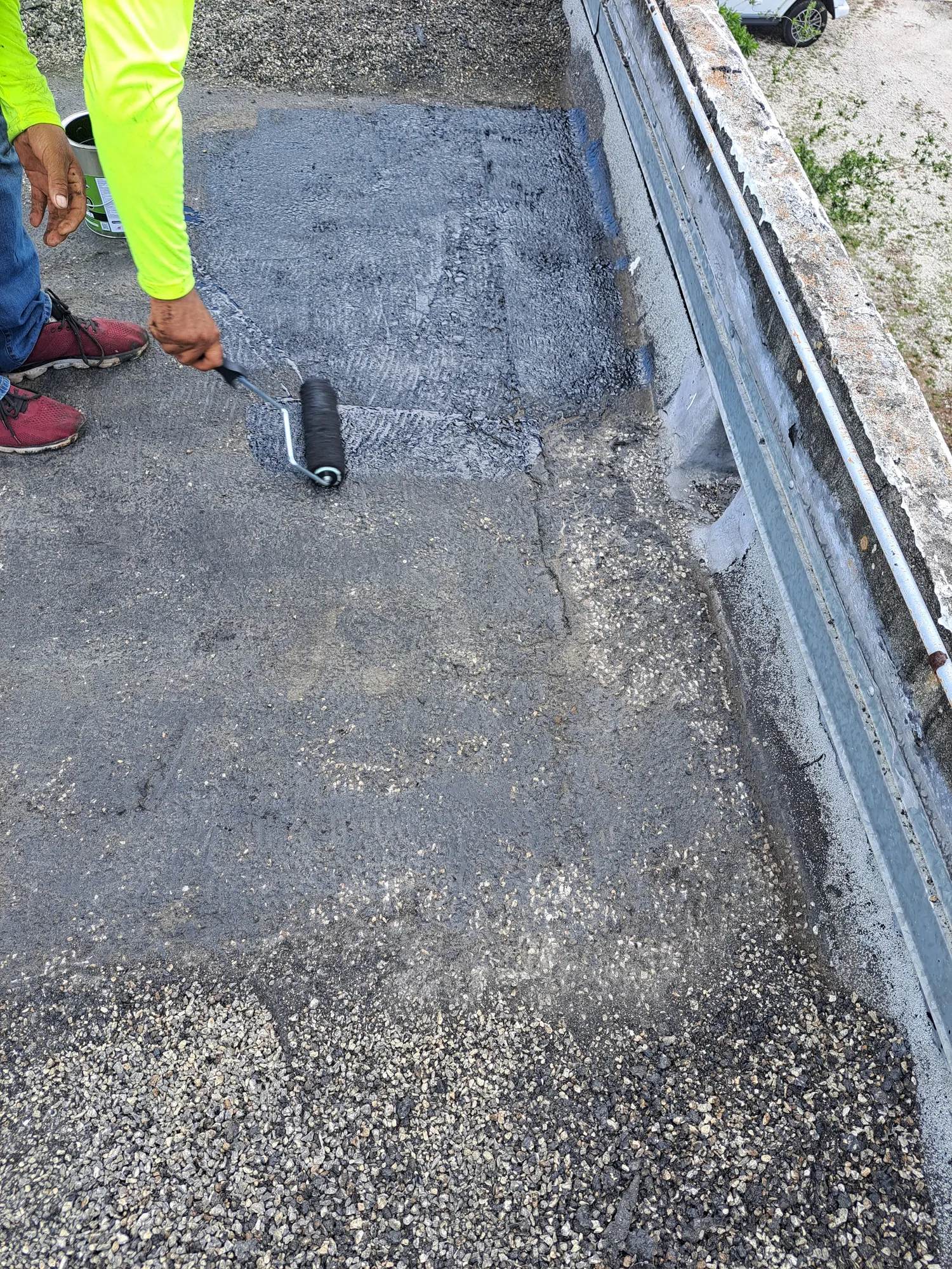 DR Construction & Roofing technician working on a commercial flat roof with a Broward County high-rise in the background